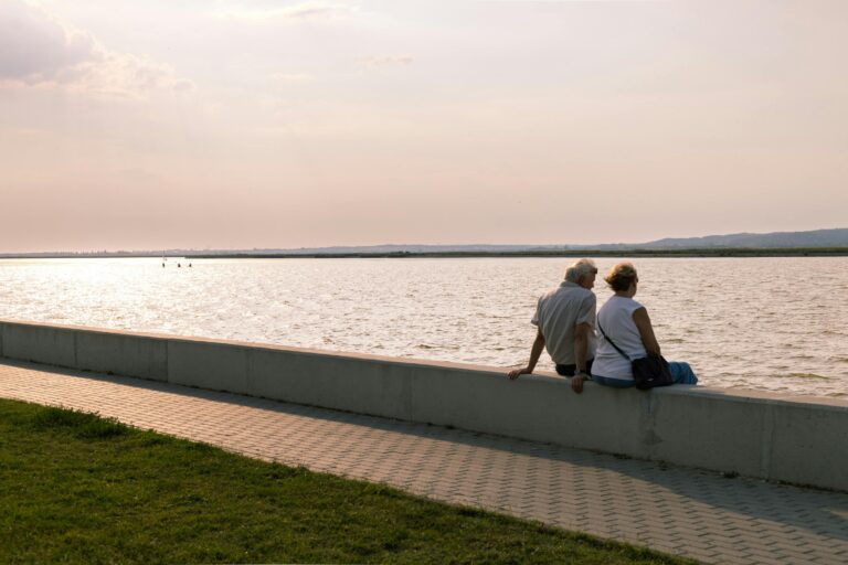 Old couple watching the sunset at the lake