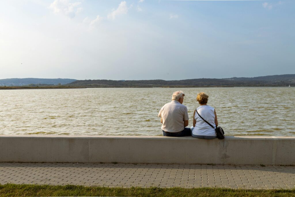 Old couple sitting by the lake at sunset
