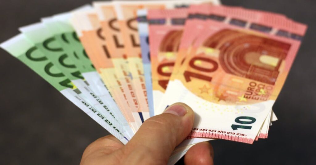 A fan of euro banknotes in various denominations held in a hand.