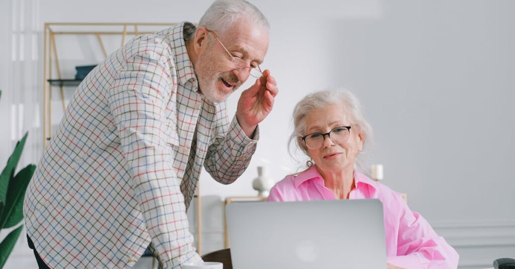 Senior couple enjoying a conversation while using a laptop indoors, showcasing active lifestyle.