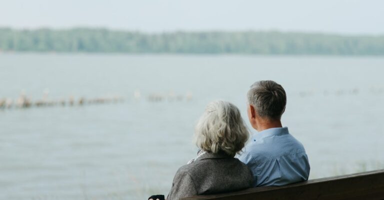 Senior couple sitting on a bench, enjoying a peaceful view by the lake.