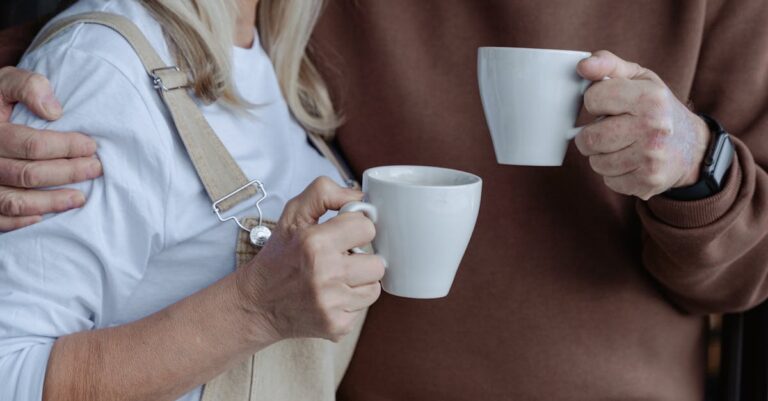 An elderly couple enjoying warm drinks in a cozy home setting.