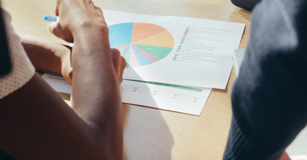 Two professionals collaborate on a project, examining a colorful pie chart in an office setting.
