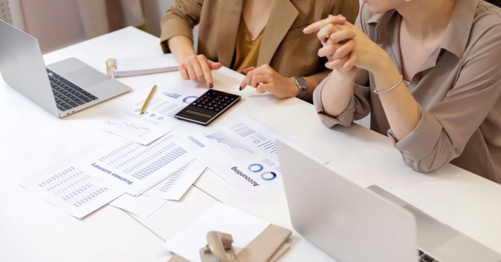Two professionals collaborating on financial documents in a modern office setting.